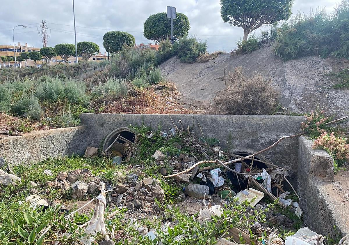 Imagen principal - En la imagen superior, tres pequeños tubos, ahora taponados, por los que, se supone, ha de pasar el agua que baja por Las Manolitas. Debajo, efecto represa de varios postes en un punto donde una edificación redujo a un pasadizo al barranco de Las Manolitas. Y finalmente, boca de apenas 50 o 60 centímetros por la que la playa de Salinetas espera que pase todo lo que baje por el barranco.