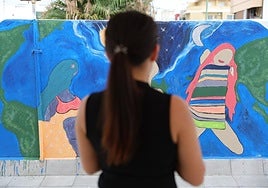 Martina, superviviente de la trata, frente a un mural pintado por mujeres atendidas en el Centro Lugo de Cáritas Diocesana de Canarias.