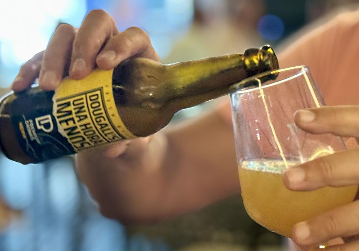 Persona echando la cerveza «Una Hora Menos» en una copa.