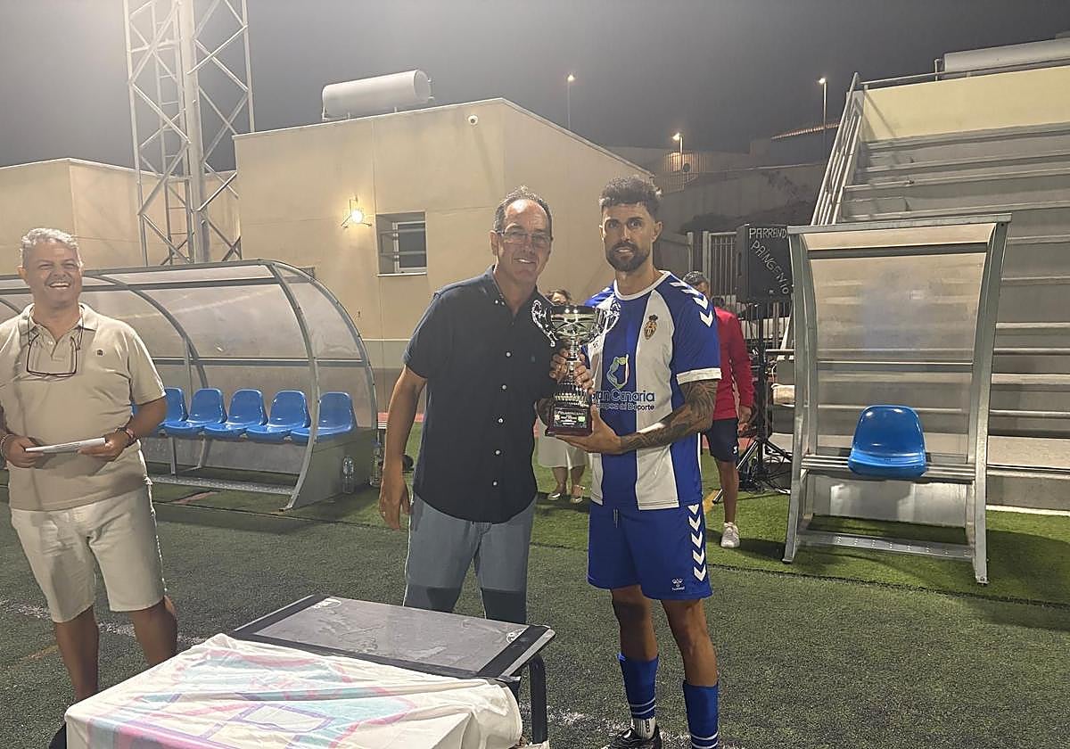 Juani Guedes, entregando el trofeo de campeón del 52º Memorial Juanito Guedes al capitán del Sporting San José.