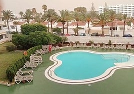 Un socorrista recoge las hamacas de una piscina de Maspalomas bajo el cielo encapotado.