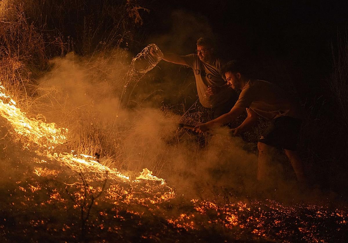 Vecinos de la localidad trabajan la madrugada de este domingo en labores de extinción del incendio forestal de A Rúa (Ourense).