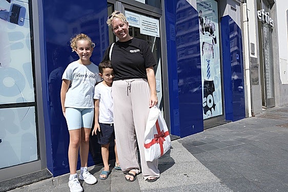 Ariadna junto a sus dos hijos con los uniformes del nuevo curso recién comprados.