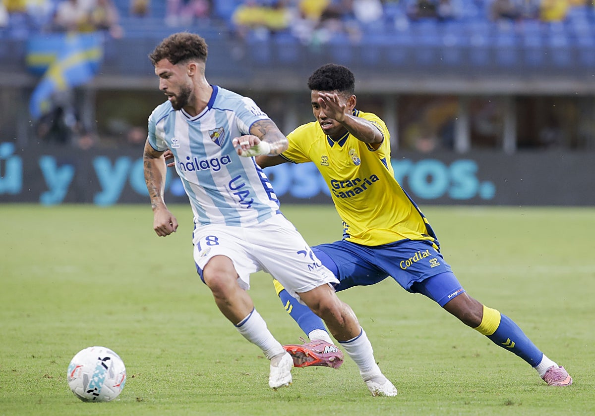 Marvin golpea el balón ante la mirada de un jugador del Málaga.