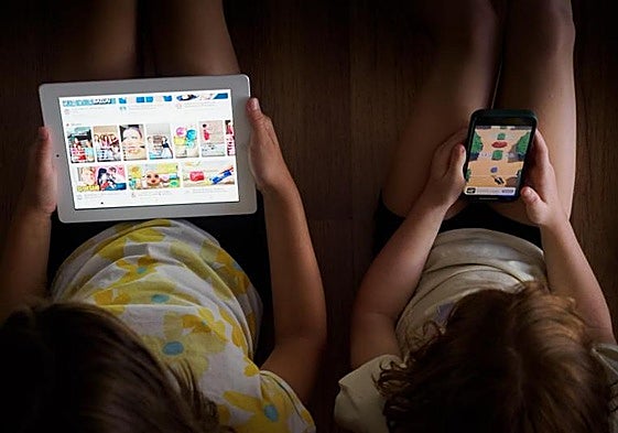 Imagen de archivo de dos menores viendo contenidos digitales.