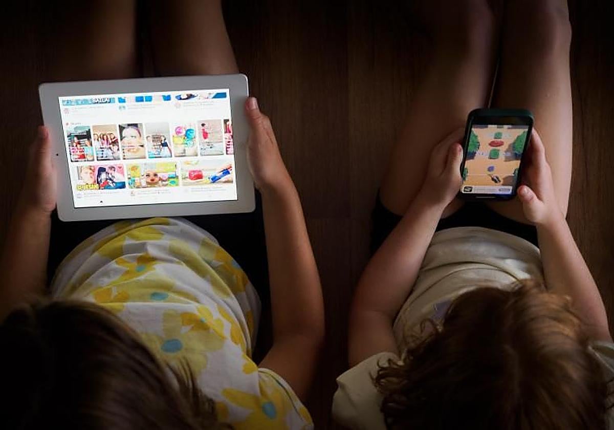 Imagen de archivo de dos menores viendo contenidos digitales.