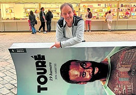 Jon Arretxe, junto a un cartel anunciador de Touré, el personaje que protagoniza su saga de novelas y que ha inspirado una serie de televisión.