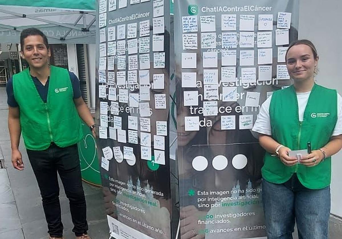 Dos voluntarios junto al panel cubierto de mensajes.