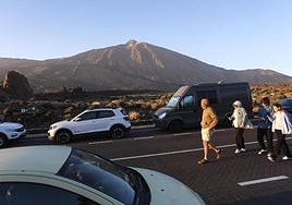 Un grupo de personas pasea junto a varios vehículos por el Parque Nacional del Teide.