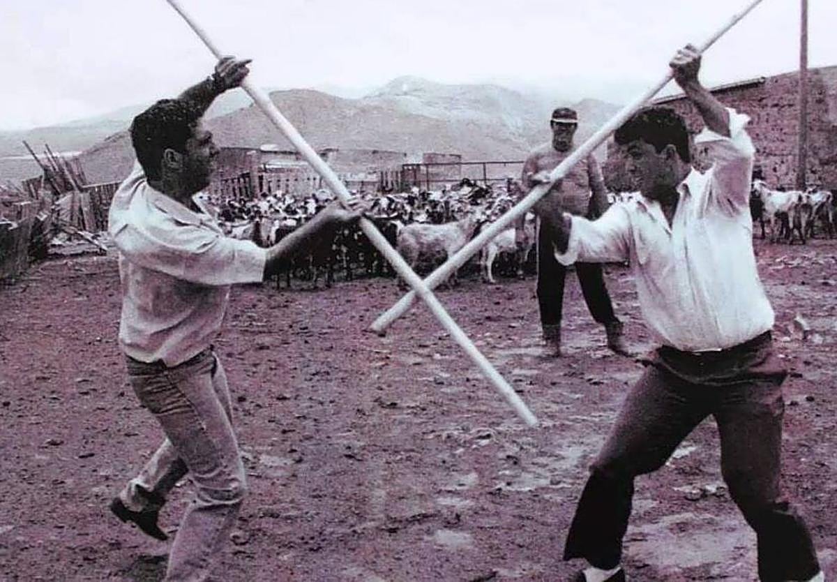 Foto antigua de dos personas practicando el Juego del Garrote Tradicional.
