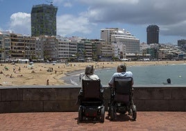 Dos personas con movilidad reducida toman el sol en el paseo de Las Canteras, en la capital grancanaria.