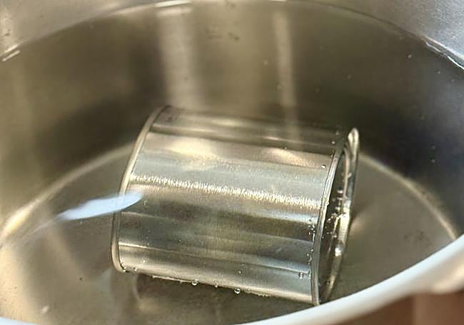 La lata de leche cubierta por agua en la olla a presión