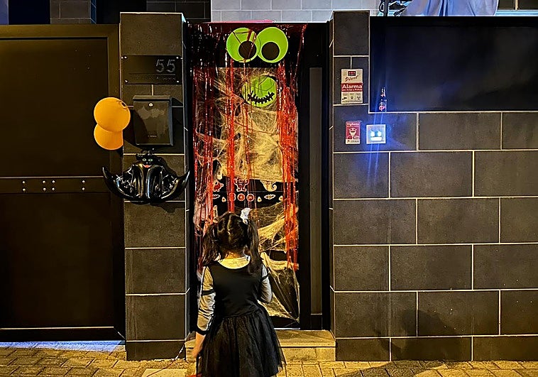 Imagen de una niña tocando en una casa decorada con temática Halloween.