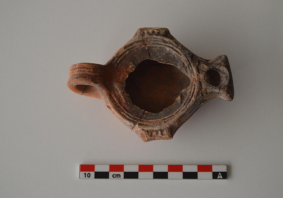 Imagen principal - La lucerna del yacimiento del taller de púrpura romano de Lobos que puede verse en el Museo Canario, en Las Palmas de Gran Canaria.