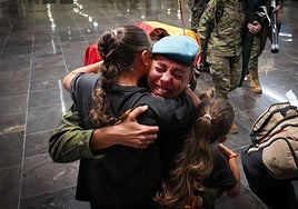 Imagen de una de las militares abrazada a dos niñas pequeñas.