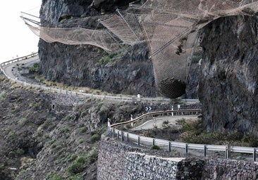 Vista parcial del tramo cerrado de la GC-200 donde se aprecia la bola de piedras suspendida en una malla de contención.