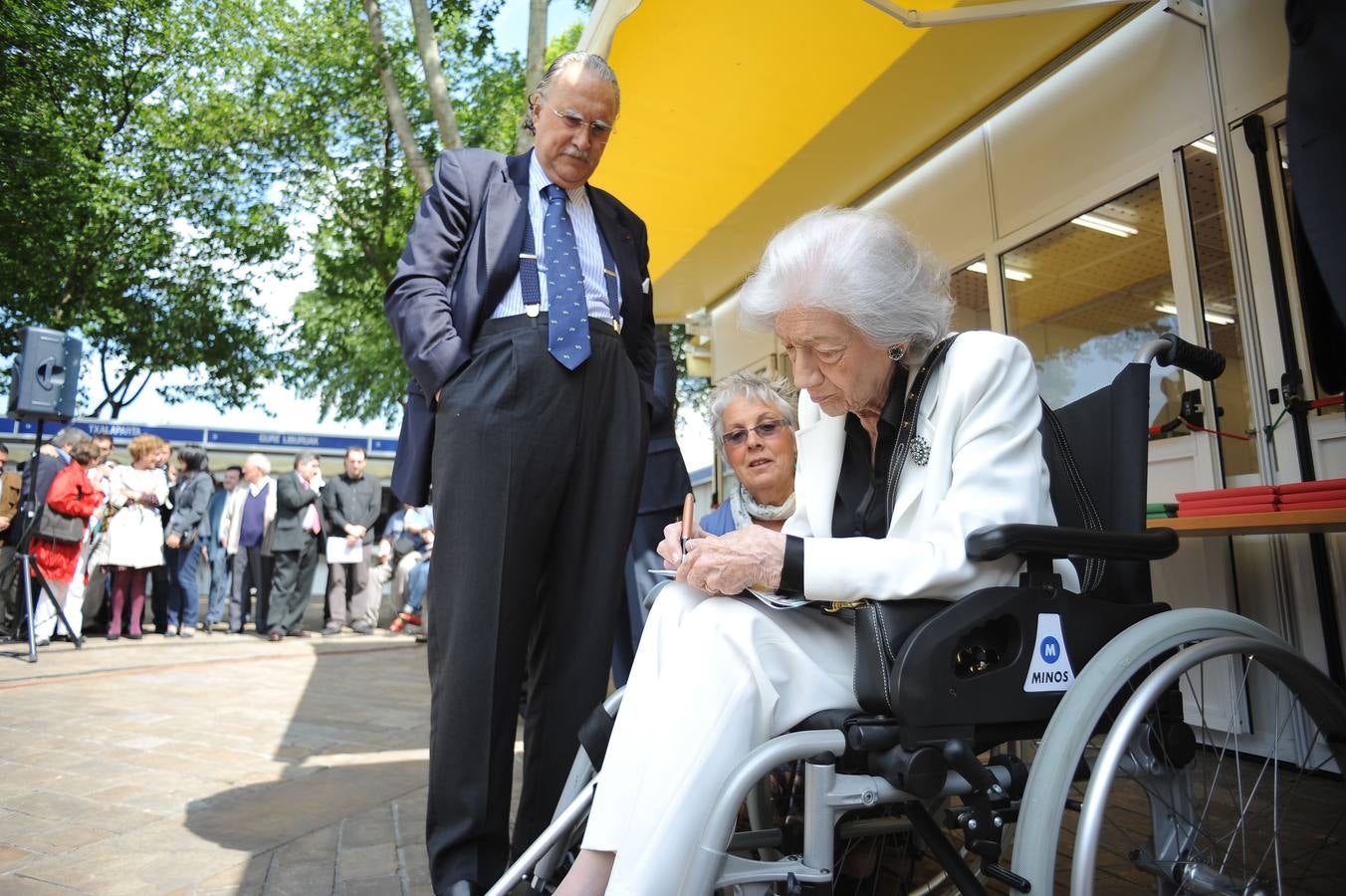 La escritora Ana Maria Matute firmando un libro ante la mirada del alcalde Iñaki Azkuna, en la inauguracion de la Feria del Libro de Bilbao