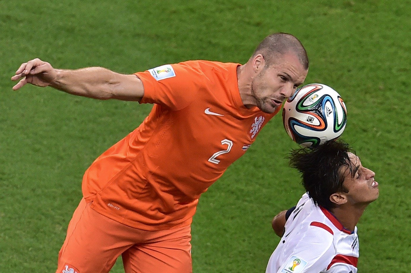 Vlaar cabecea el balón ante un defensor de Costa Rica.