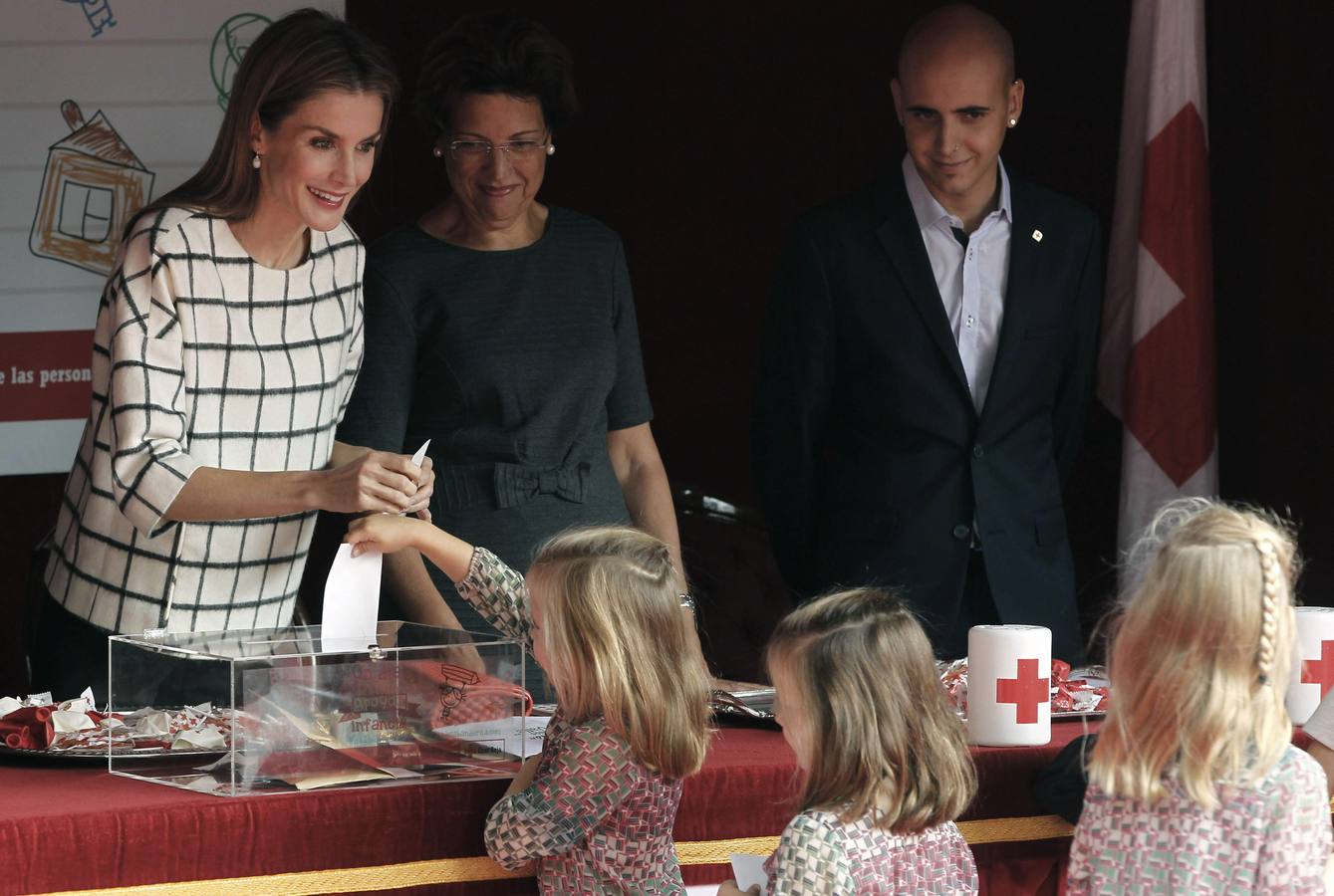 La reina Letizia recibe las aportaciones de unas niñas que se han acercado a las puertas del Congreso, donde ha presidido por primera vez la mesa de cuestación de la Cruz Roja, para apoyar así la celebración del Día de la Banderita.