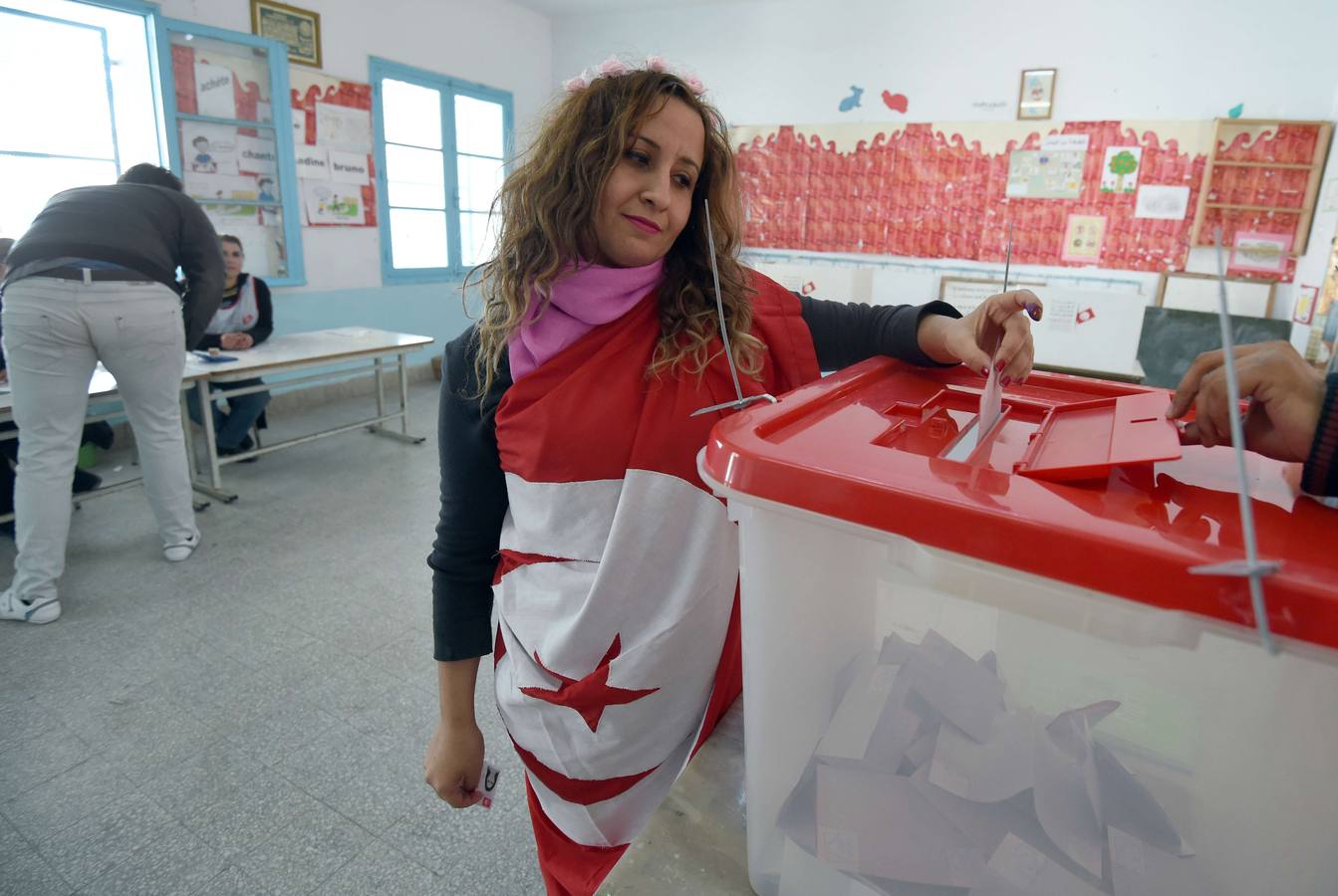 Elecciones en Túnez. Una tunecina ejerce su derecho al voto envuelta en la bandera nacional.