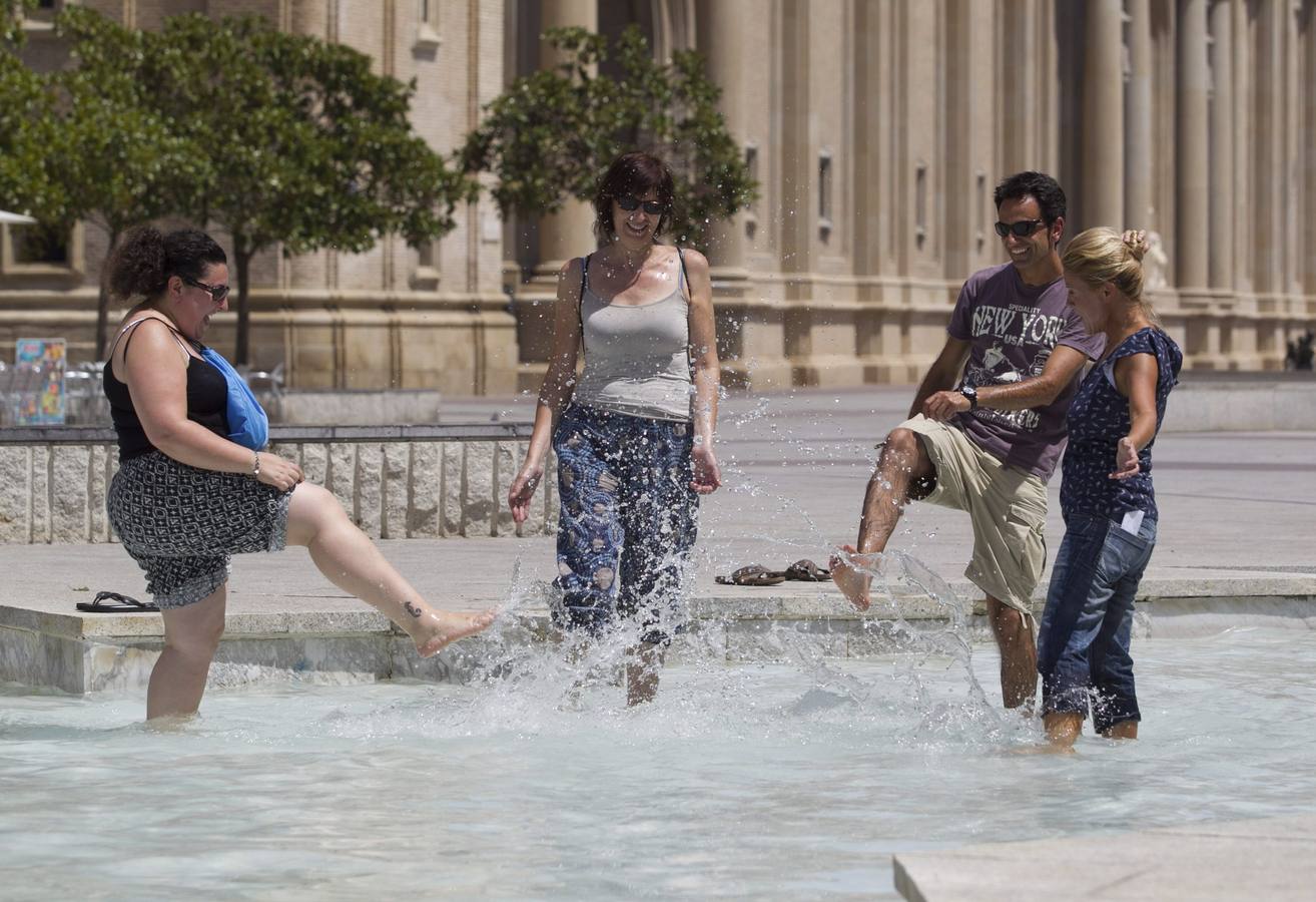 Unos turistas se refrescan en una de las fuentes en Zaragoza.