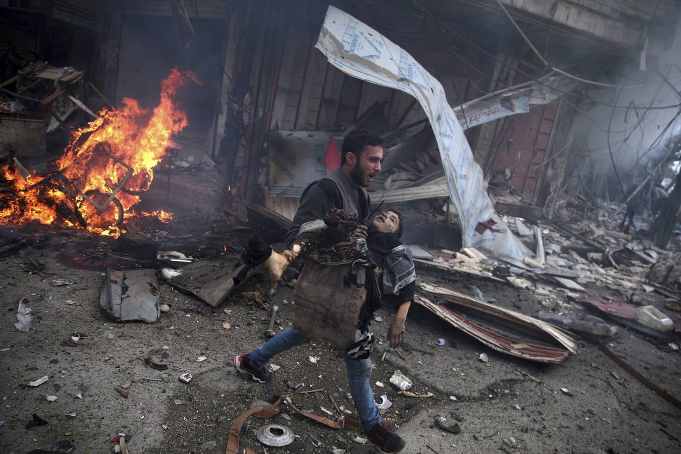 Foto de la serie ganadora del segundo premio 'Temas de actualidad'. La fotografía muestra a un hombre sirio portando el cuerpo sin vida de un niño asesinado durante los bombardeos efectuados en la ciudad de Douma (Siria) el 7 de noviembre 2015.