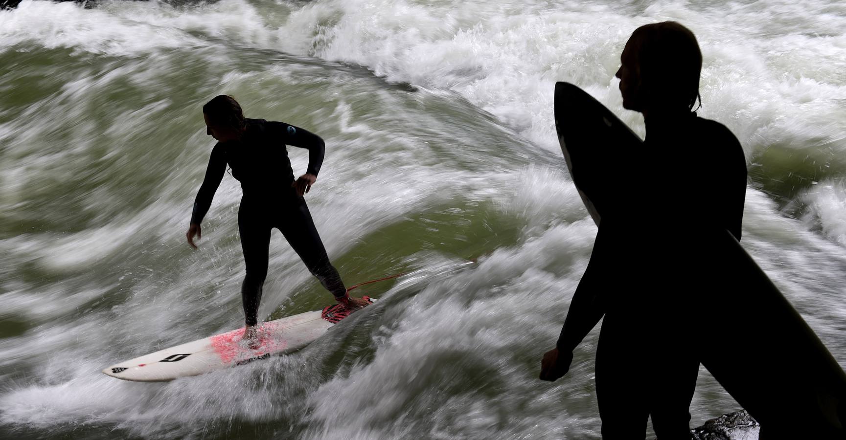 Jóvenes practican surf en el canal de Eisbach, al sur de Alemania