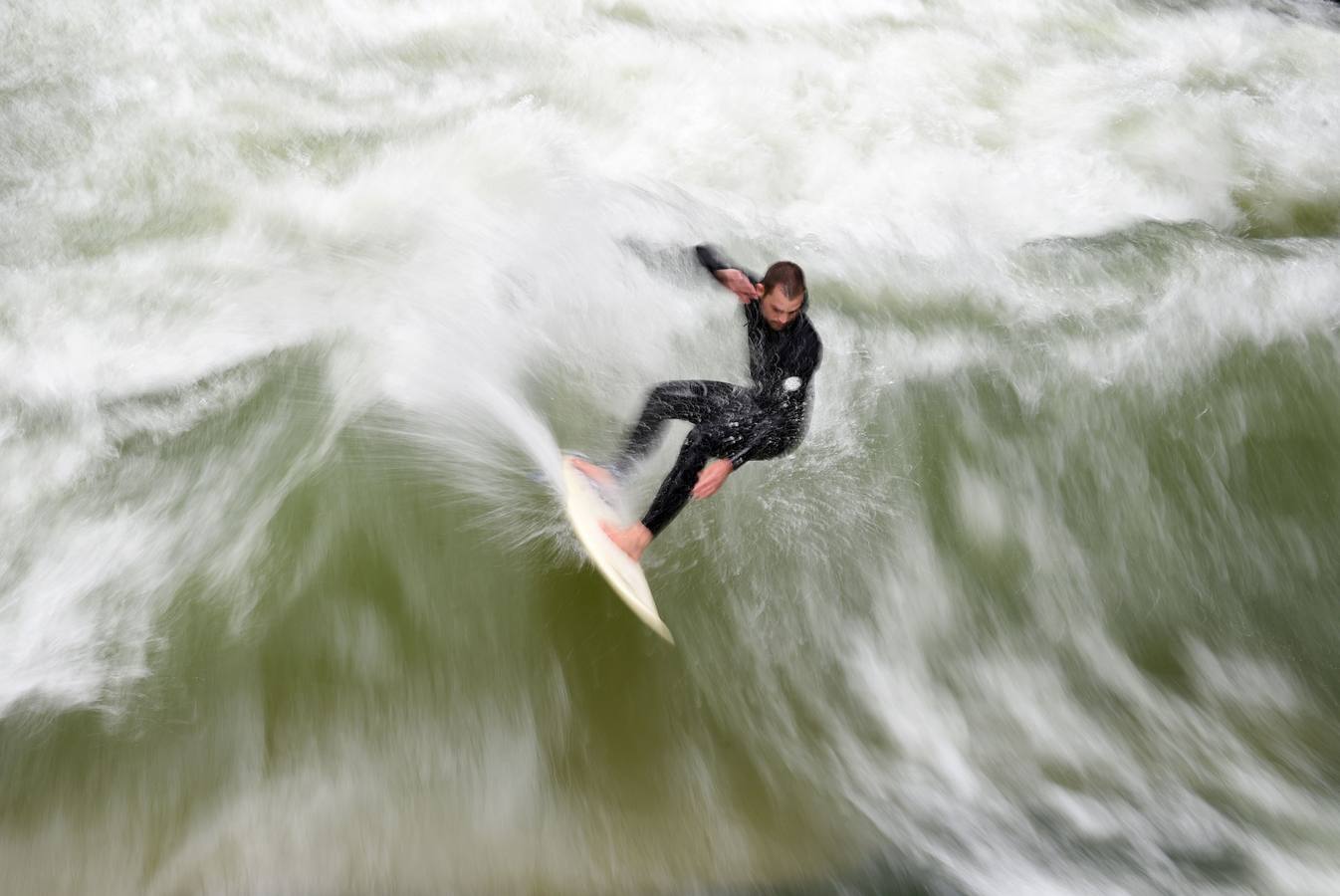 Jóvenes practican surf en el canal de Eisbach, al sur de Alemania