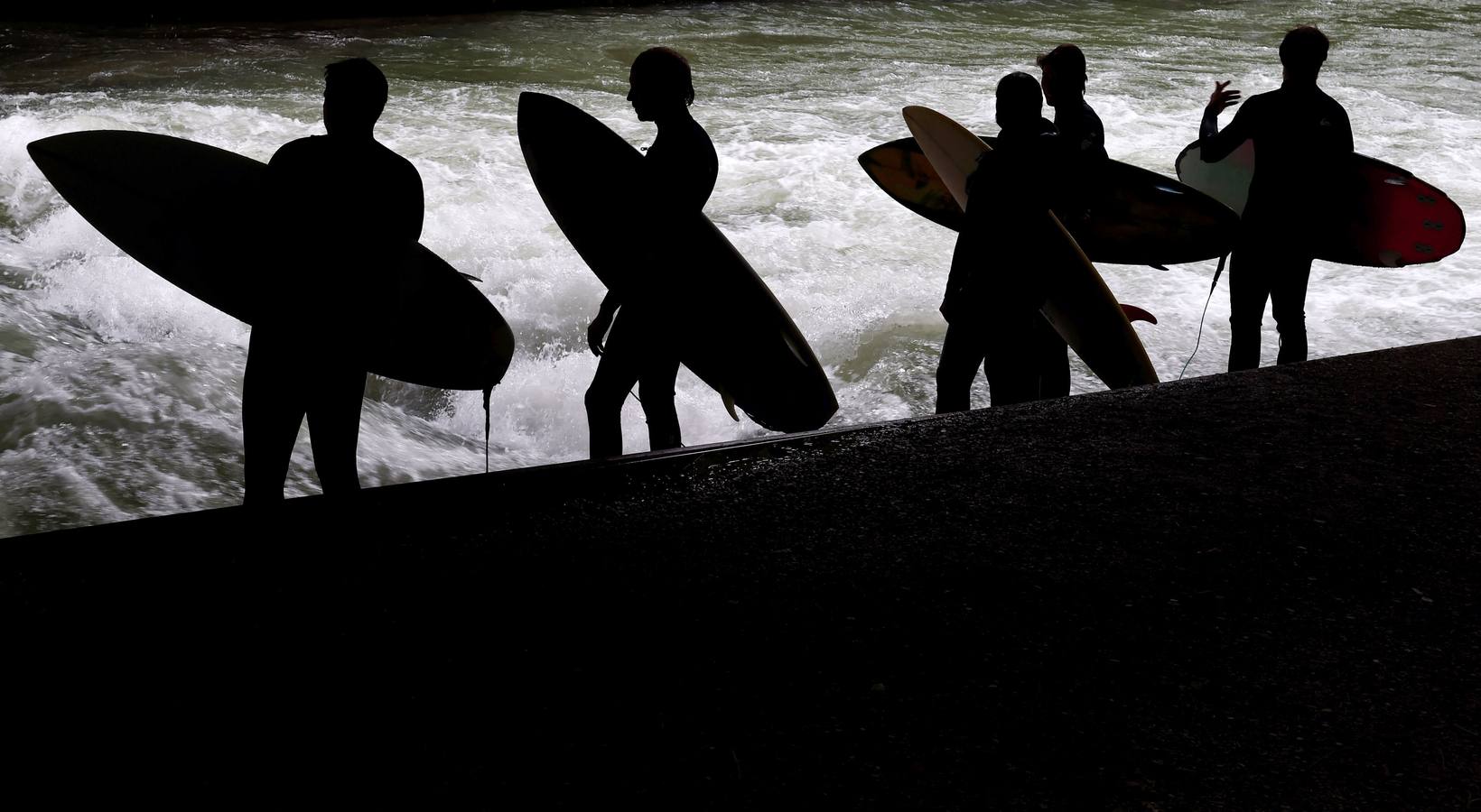 Jóvenes practican surf en el canal de Eisbach, al sur de Alemania