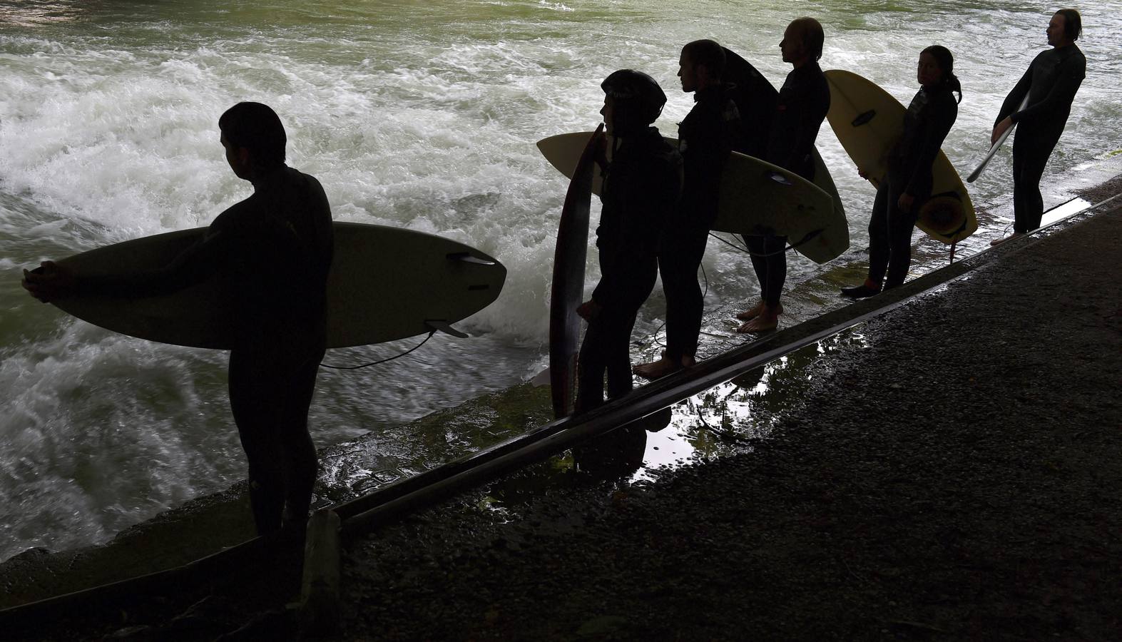 Jóvenes practican surf en el canal de Eisbach, al sur de Alemania