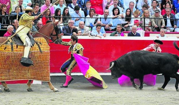 Alberto Lamelas trata de refugiarse en el burladero mientras el toro hace hilo por él. :: J. M. lópez