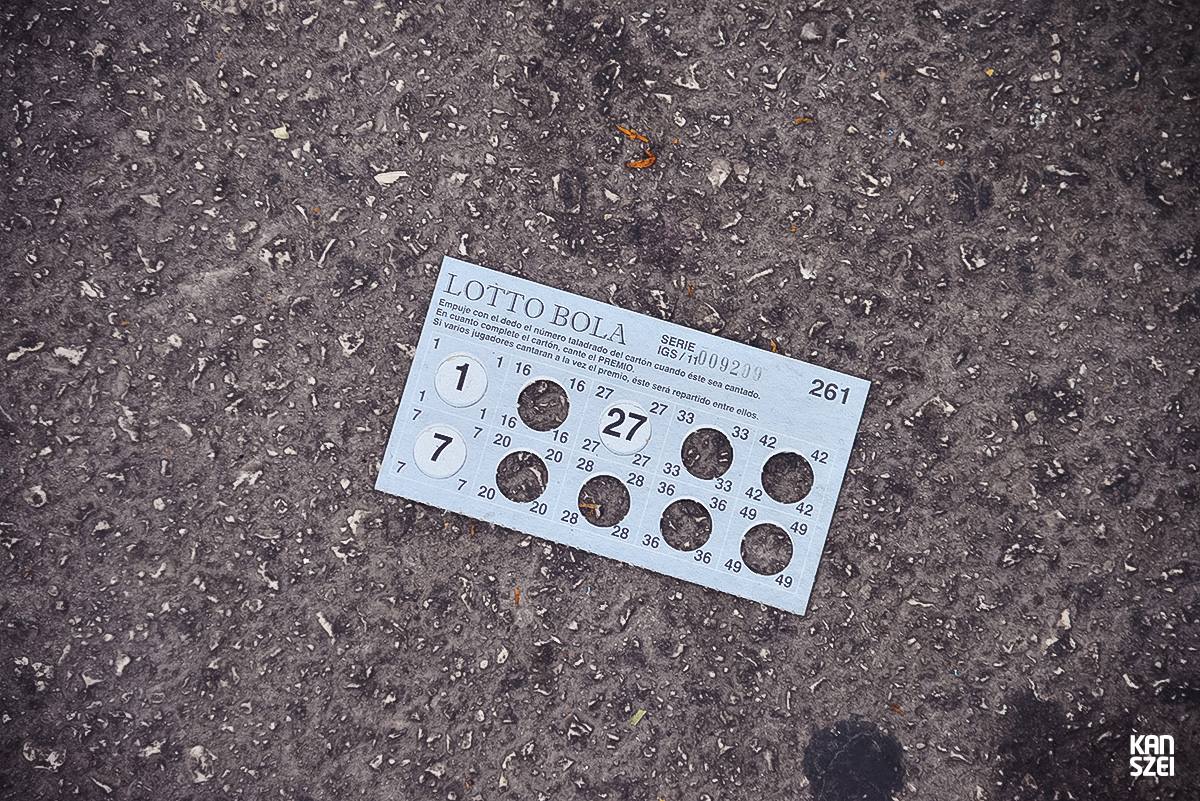 «A tus pies se llama este conjunto de fotografías que nos hacen inclinar la cabeza hacia abajo y dejar de mirar al cielo, las atracciones y el resto de cosas que se encuentran a simple vista. Una colección de objetivos perdidos, olvidados y/o desechados con una historia individual desconocida, perfecta para nutrir nuestra imaginación particular»