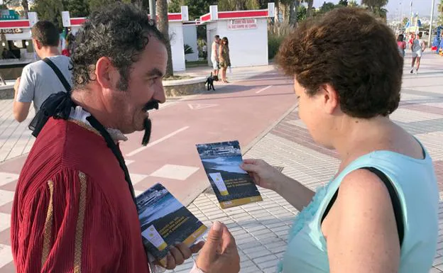 Un actor caracterizado de Miguel de Cervantes entrega un folleto a una mujer.