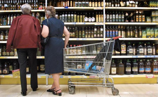 Una pareja examina varias botellas de aceite en un supermercado.