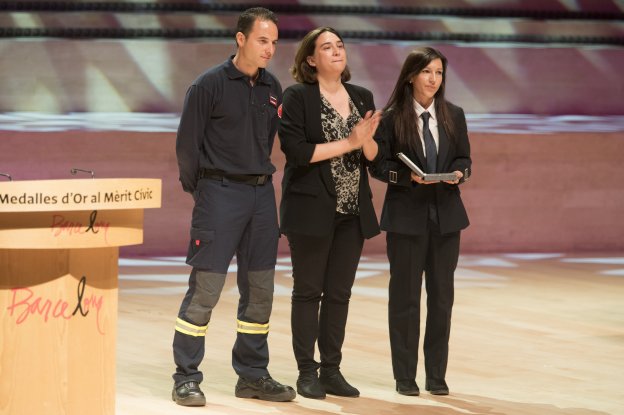 Colau, emocionada junto a dos bomberos durante el acto de entrega ayer de la medallas. :: m. pérez / efe