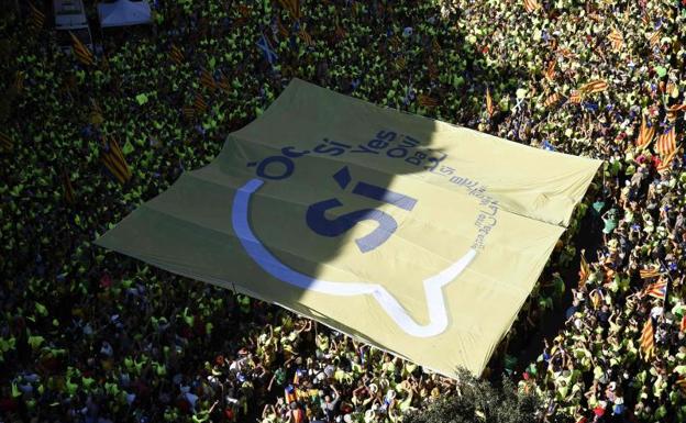Cientos de personas sostienen una pancarta gigante con la leyenda 'Sí', en varios idiomas.