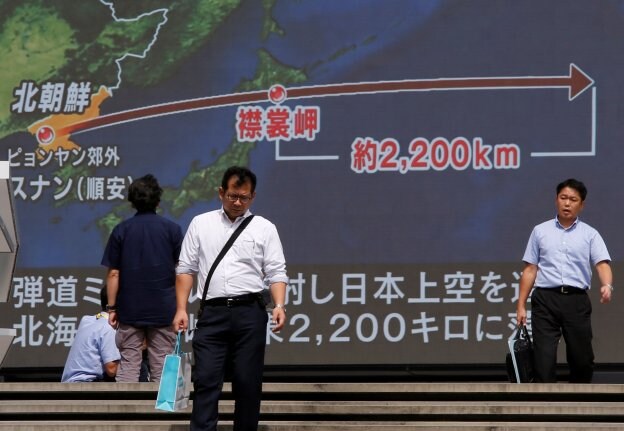 Transeúntes pasan frente a una pantalla gigante que describe la trayectoria del misil norcoreano en Tokio. :: Issei Kato / reuters

