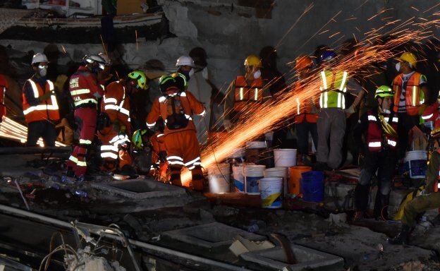 Los equipos de rescate cortan una columna metálica para intentar retirar los escombros en un edificio de la capital. :: YURI CORTEZ / afp