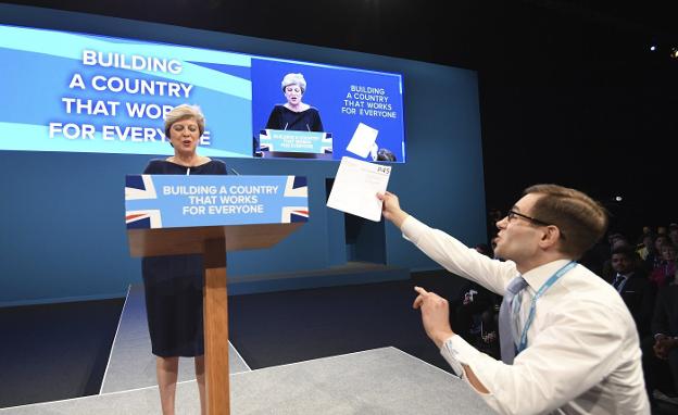 Un cómico trata de entregarle a Theresa May el documento oficial que se usa en Reino Unido para oficializar un despido laboral. :: f. a. / efe
