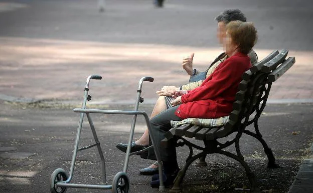 Dos ancianas descansan en un banco del jardín de una residencia geriátrica.