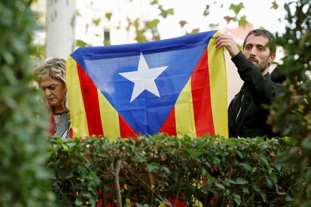 Dos personas sostienen una estelada frente a la Audiencia Nacional durante la declaración de Junqueras y los exconsejeros. :: Mariscal / efe