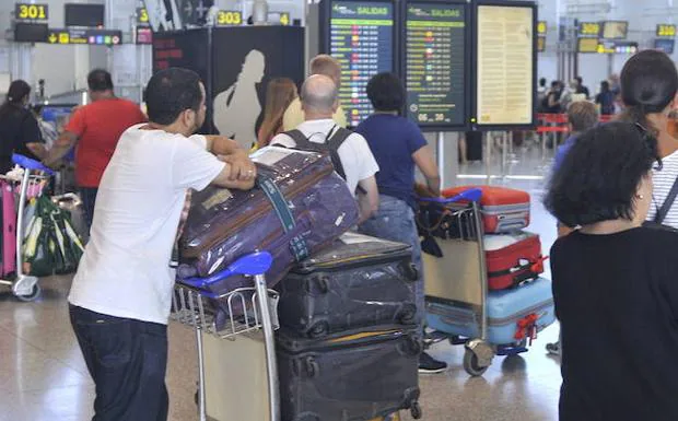 Viajeros buscan sus vuelos en una pantalla informativa .
