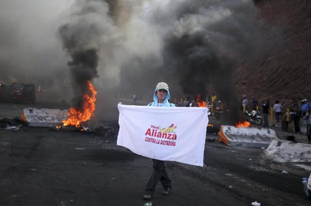 Un simpatizante de la oposición muestra una pancarta en una calle de Tegucigalpa. :: G. Amador / efe