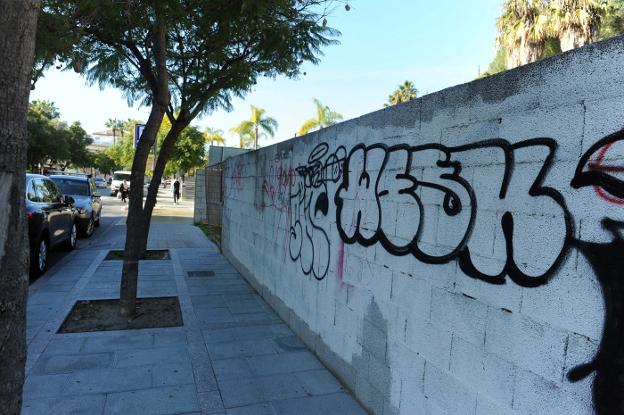 Un viandante pasa junto a un grafiti estampado en un muro de la calle Jacinto Benavente.