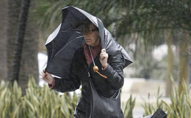 Una persona sujeta su paraguas para evitar que el fuerte viento lo arrastre (archivo). 