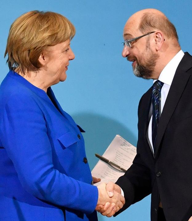 Merkel y Schulz sellan su acuerdo con un apretón de manos ante las cámaras. :: John MACDOUGALL / afp