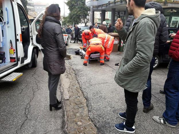 Servicios de emergencia atienden a uno de los heridos antes de trasladarlo en la ambulancia. A la derecha, Luca Traini. :: efe y afp