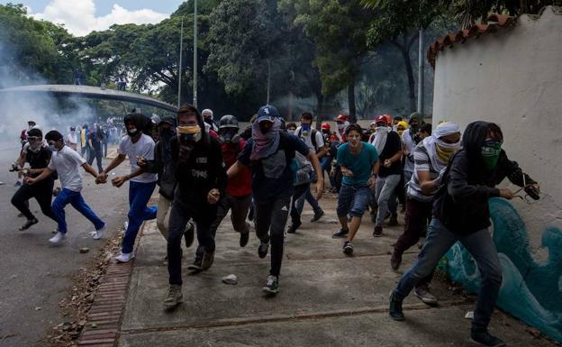 Manifestantes huyen de los antidisturbios en Caracas.