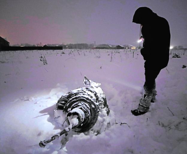 Sin luz. Un miembro de los equipos de rescate localiza los restos del Antónov entre la nieve. 