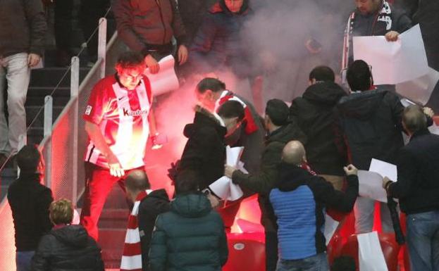 Aficionados del Athletic mitran una bengala lanzada por ultras del Marsella. 